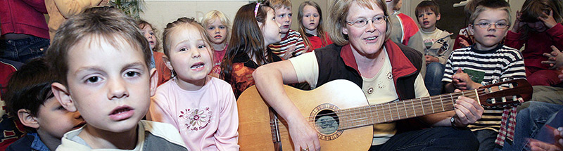 Kinder und Gitarrenspielerin im Altarraum einer Kirche